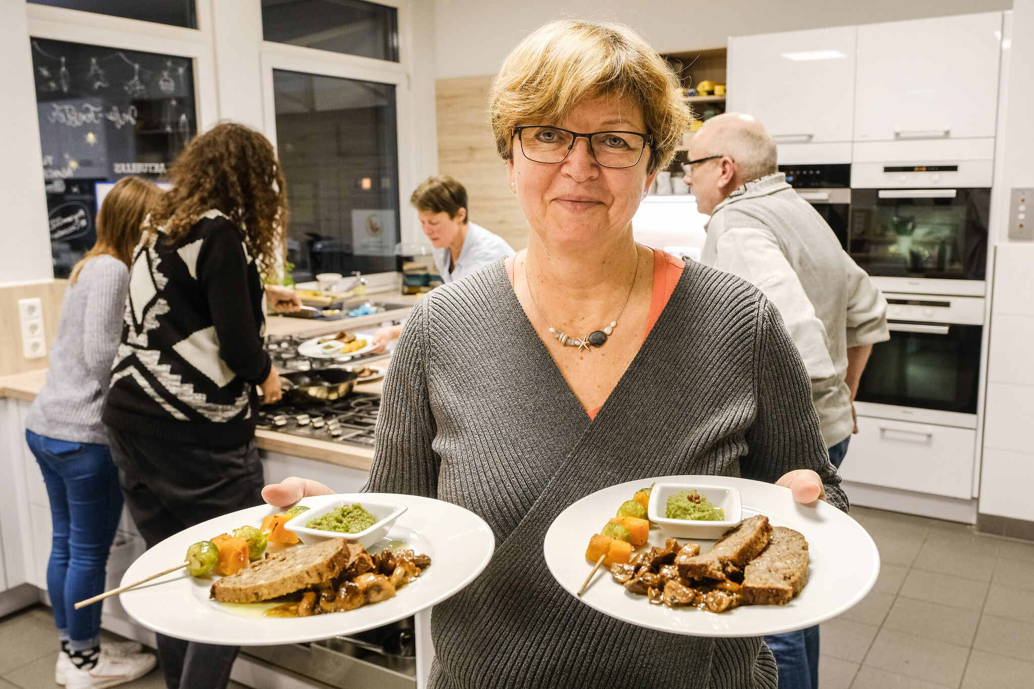 Bettina Nebe mit dem Hauptgang: Nussbraten, marinierte Mischpilze und Rosenkohl-Kürbis-Spieße mit Pesto. Ein Weihnachtsessen ganz ohne Fleisch – d​as ist der Plan bei einem Kochkurs in der Familien-Bildungsstätte. Foto: epd-bild/Jens Schulze