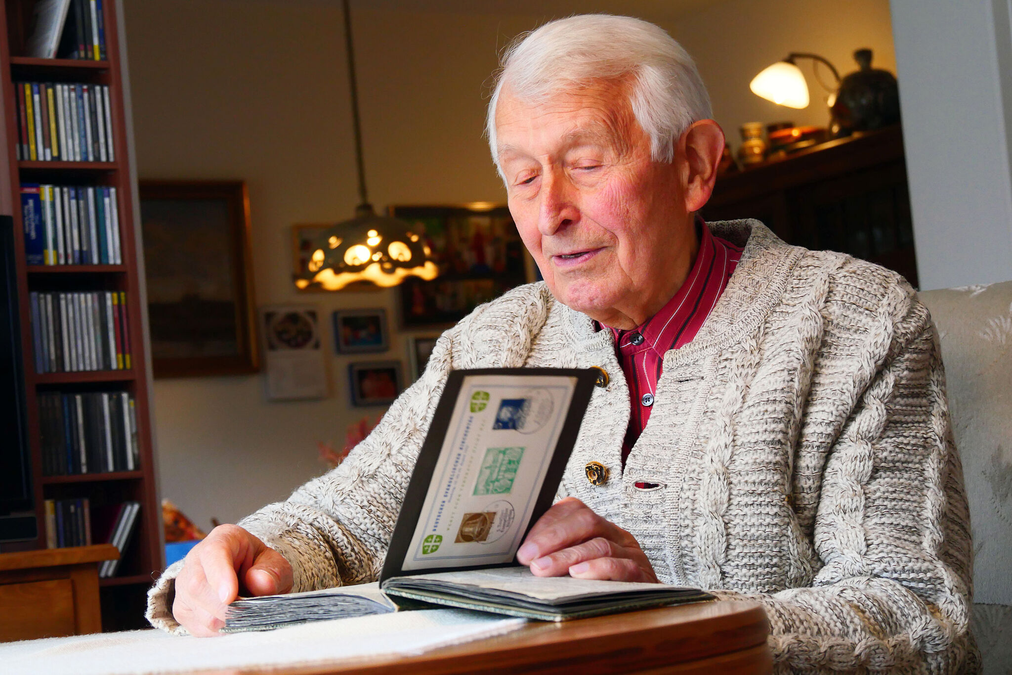 Hugo Rausch (86) blättert in seiner Lüneburger Wohnung in einem Fotoalbum aus den 1950er-Jahren. In dem Album befinden sich Fotos von den Kirchentagen 1953 in Hamburg und 1954 in Leipzig. (Foto: Carolin George)