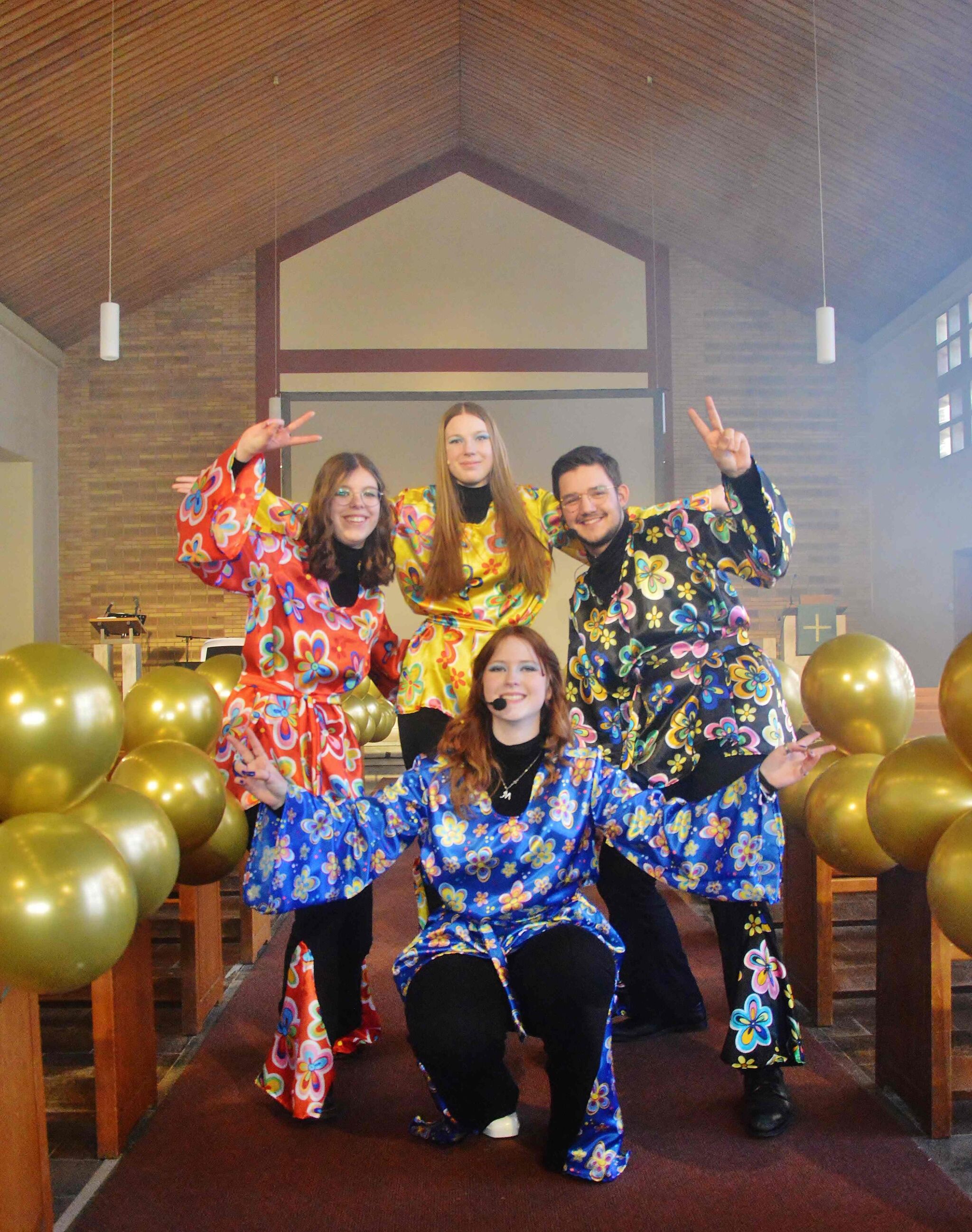 Eine Gruppe von Jugendlichen hat sich mit Abba-Kostümen verkleidet und hat sich in der Kirche aufgestellt zu einem Gruppenfoto.