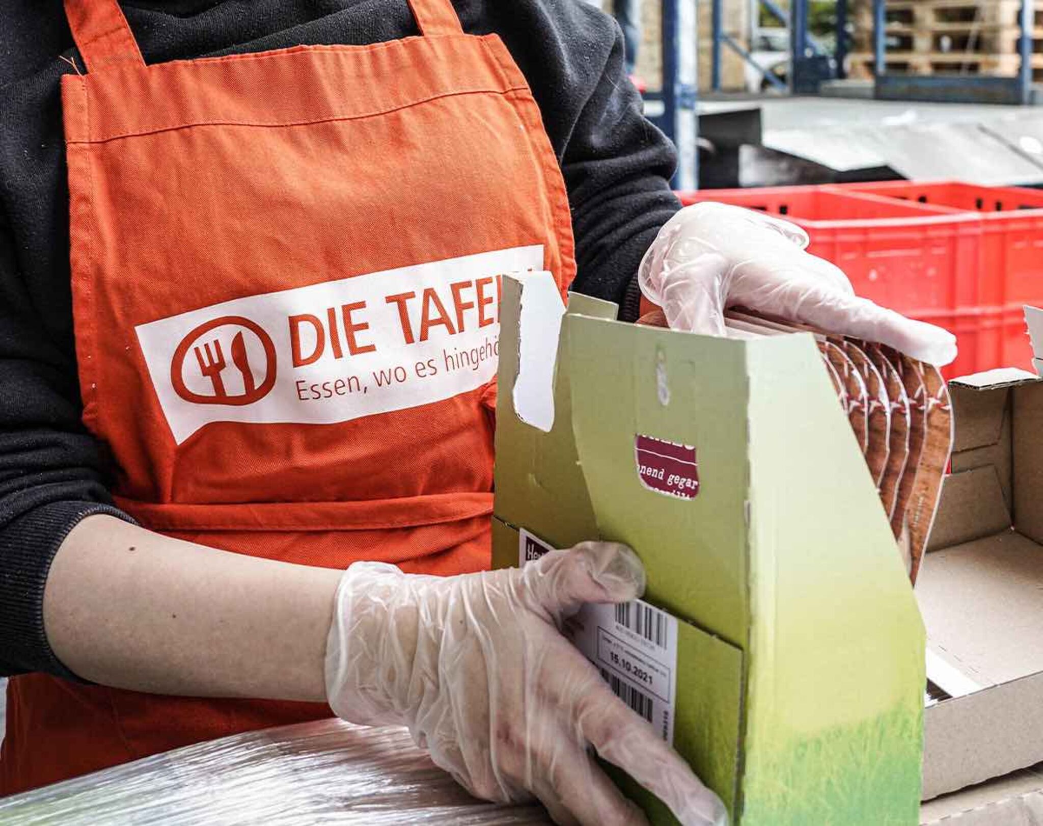 Ein Mitarbeitender der Osnabrücker Tafel verpackt Lebensmittel.