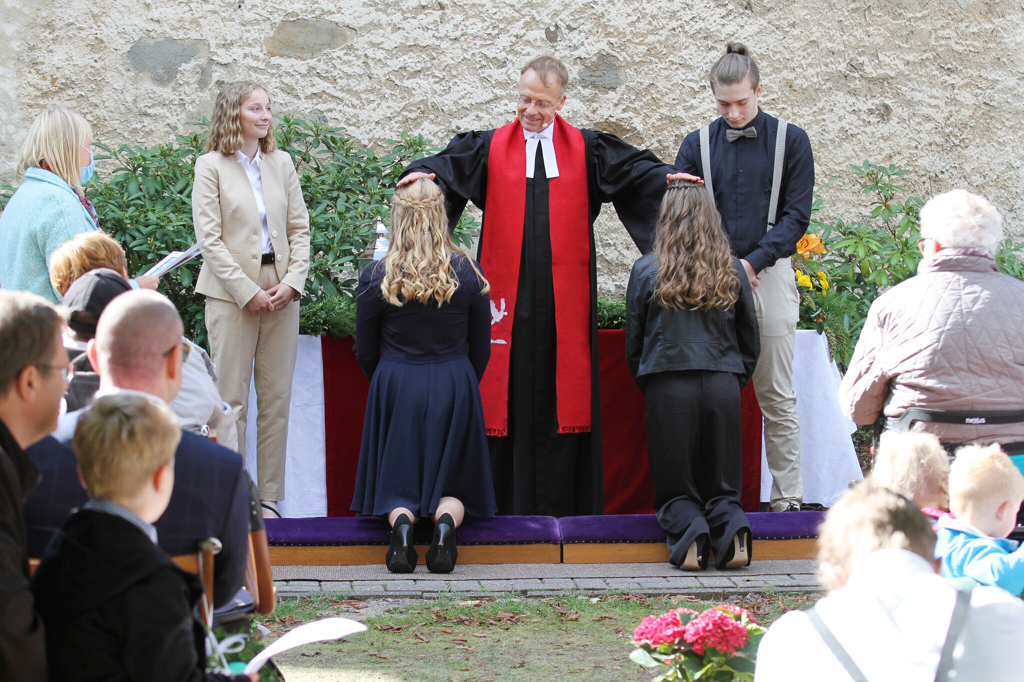 Pastor Sönke von Stemm segnet zwei Konfirmandinnen; zwei Jugendmitarbeitende assistieren ihm. Archivfoto: epd-bild/Lothar Veit