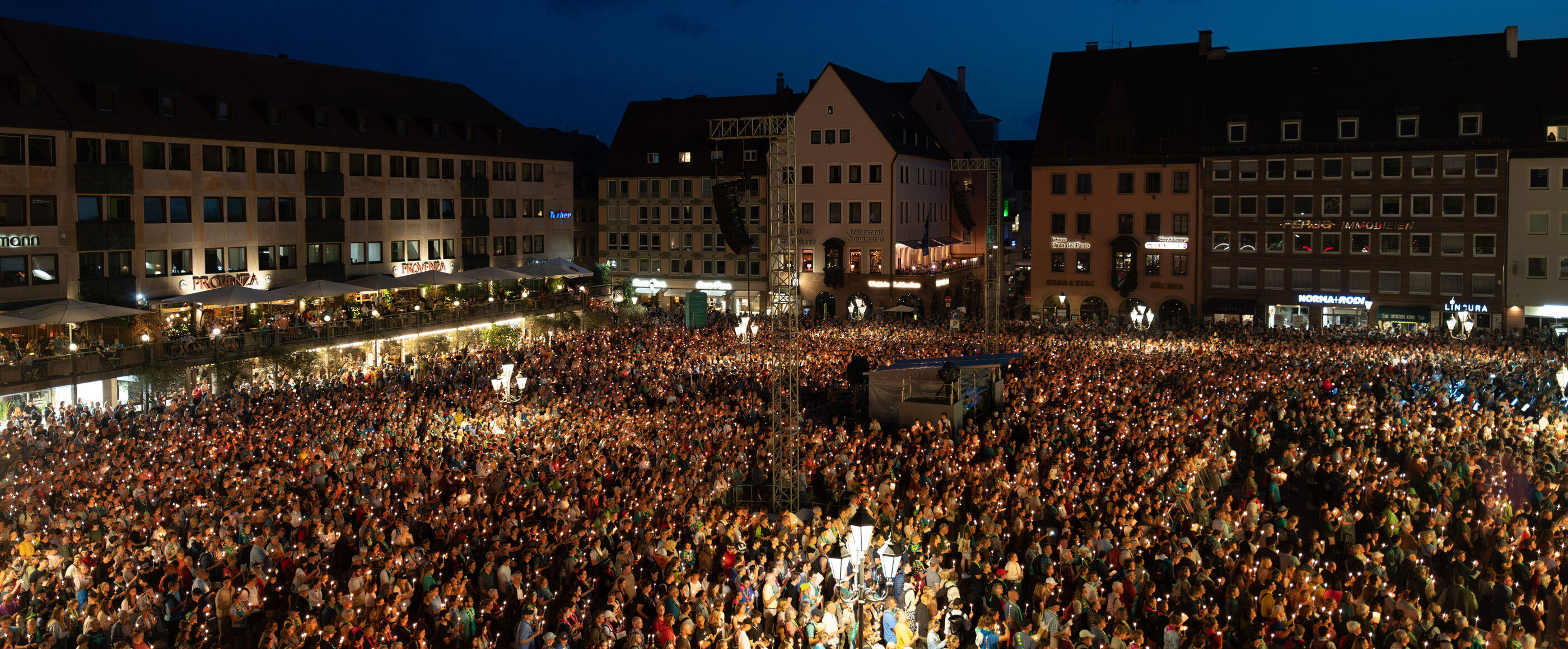 Eine Menschenmenge auf einem großen Marktplatz bei Nacht.