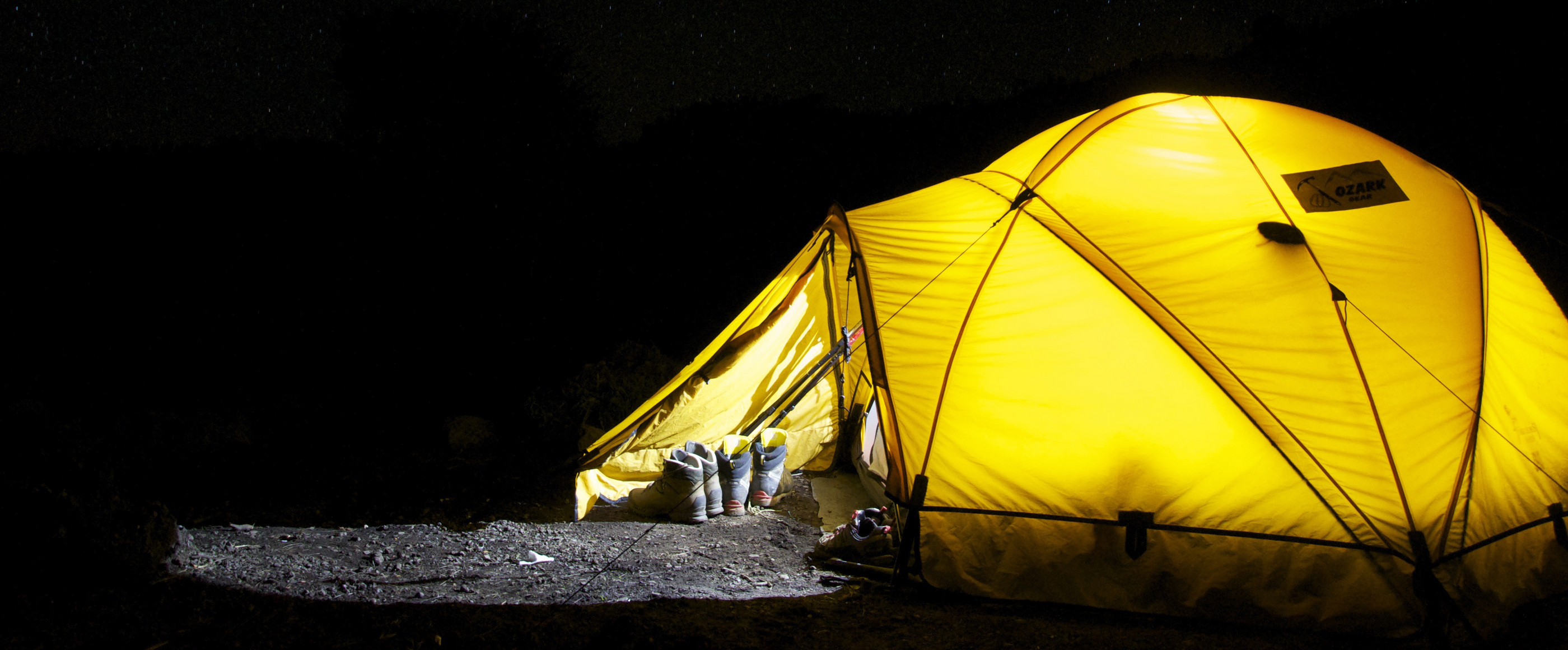 Ein von innen beleuchtetes Zelt bei Nacht.
