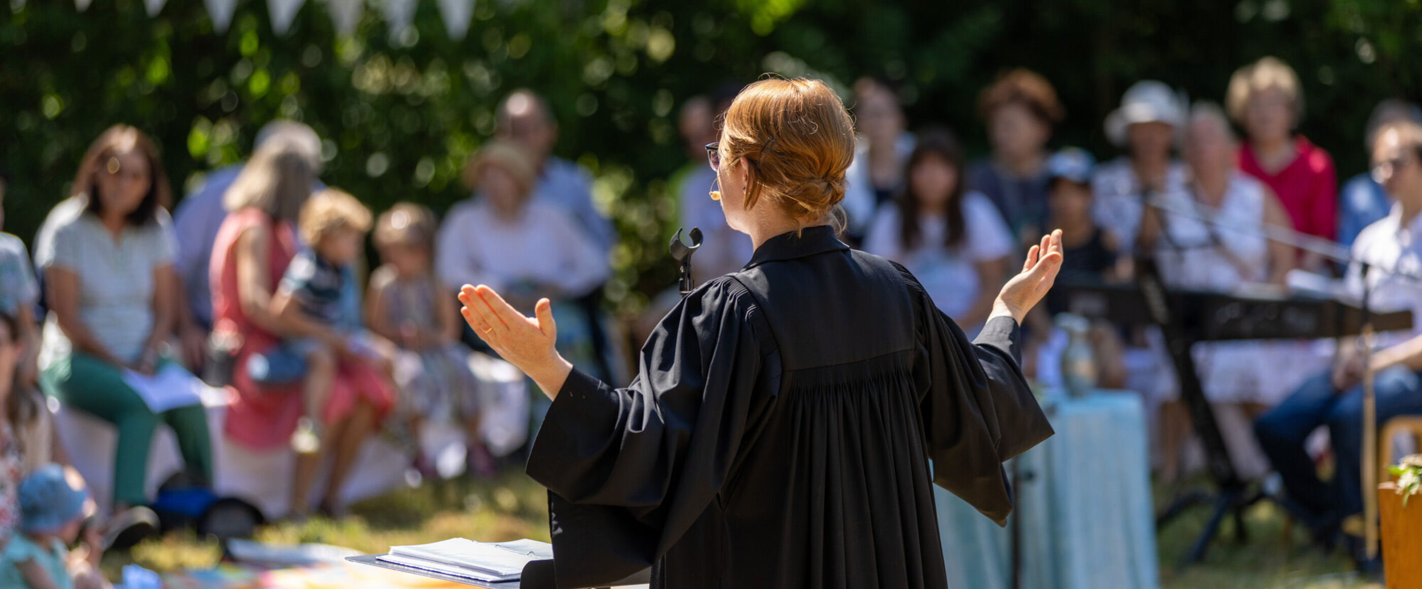 Eine Pastorin segnet die Gemeinde bei einem Freiluftgottesdienst.