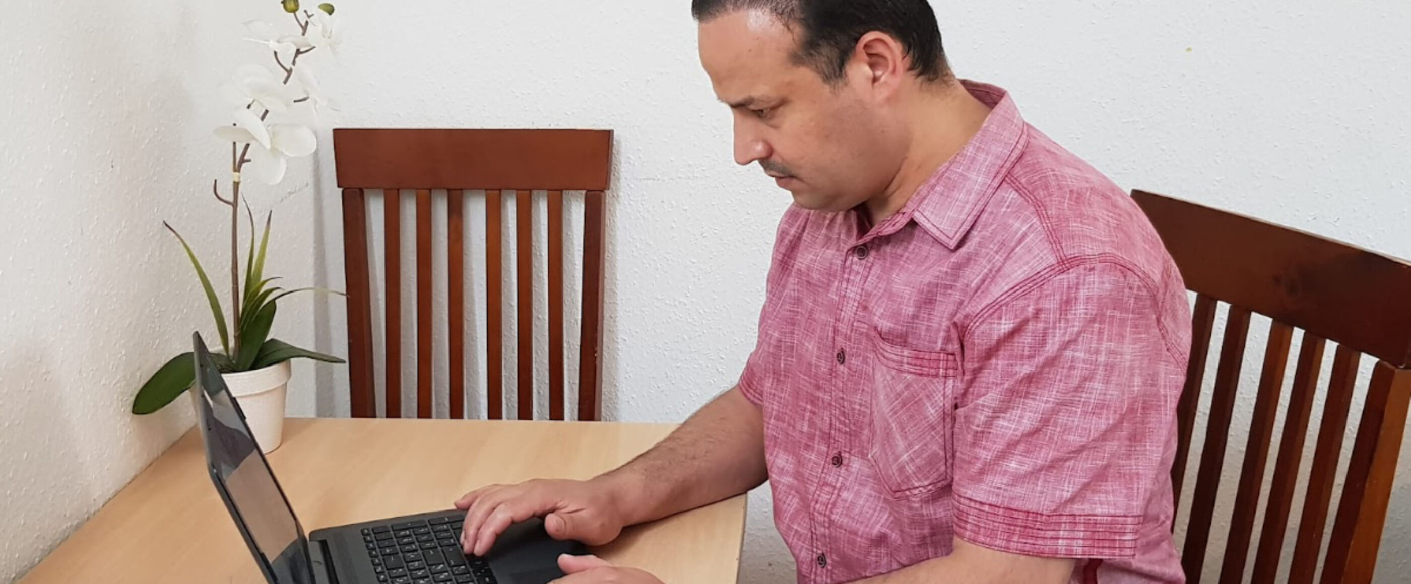 Ein Mann sitzt an einem Tisch und schreibt an einem Laptop