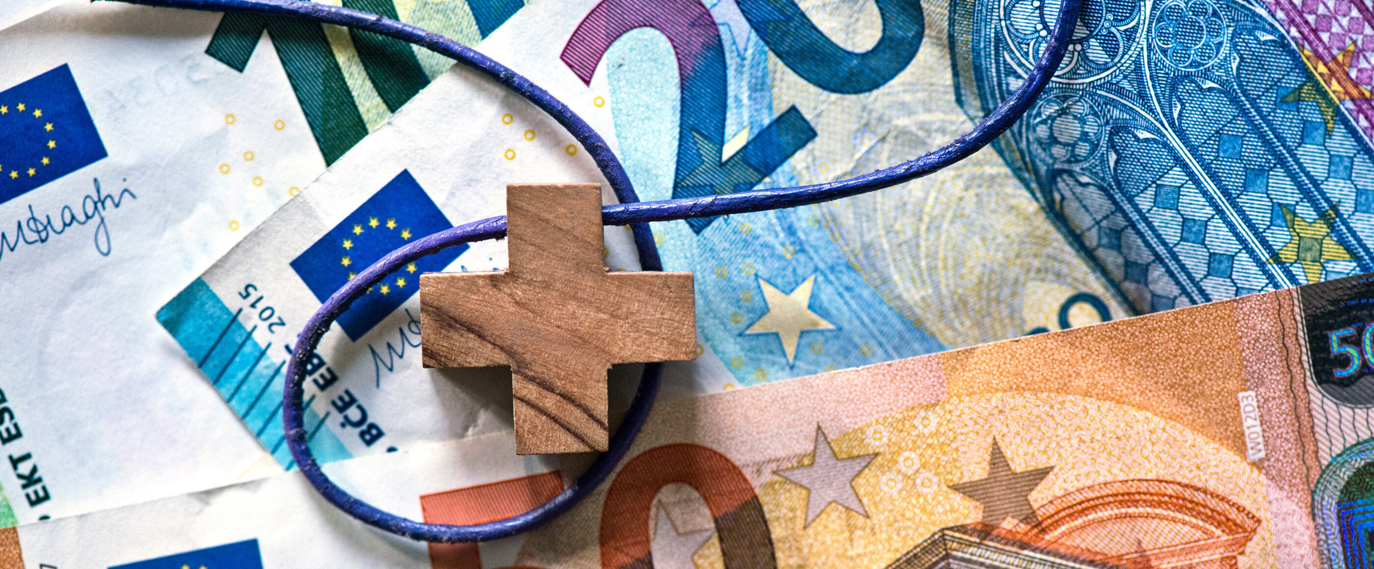 Ein Holzkreuz auf Euro-Banknoten.