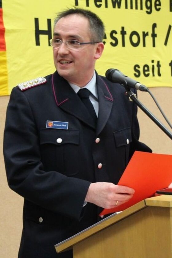 Ein Mann mit dunklen kurzen Haaren und Brille steht in Feuerwehr-Uniform vor einem Rednerpult.